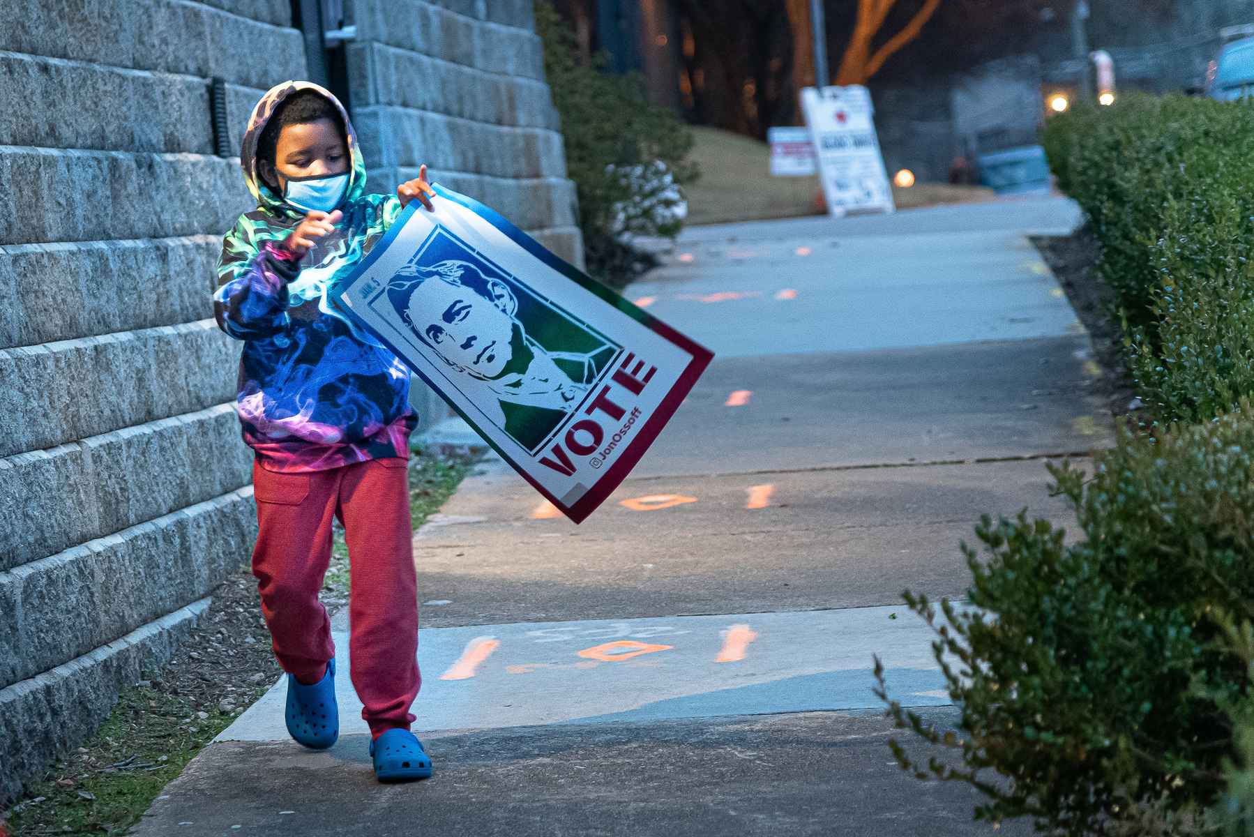 December 15, 2020 - Atlanta, GA. A child carries a Jon Ossof poster at drive-in rally for Georgia Democratic U.S. Senate candidates Jon Ossoff and Raphael Warnock.